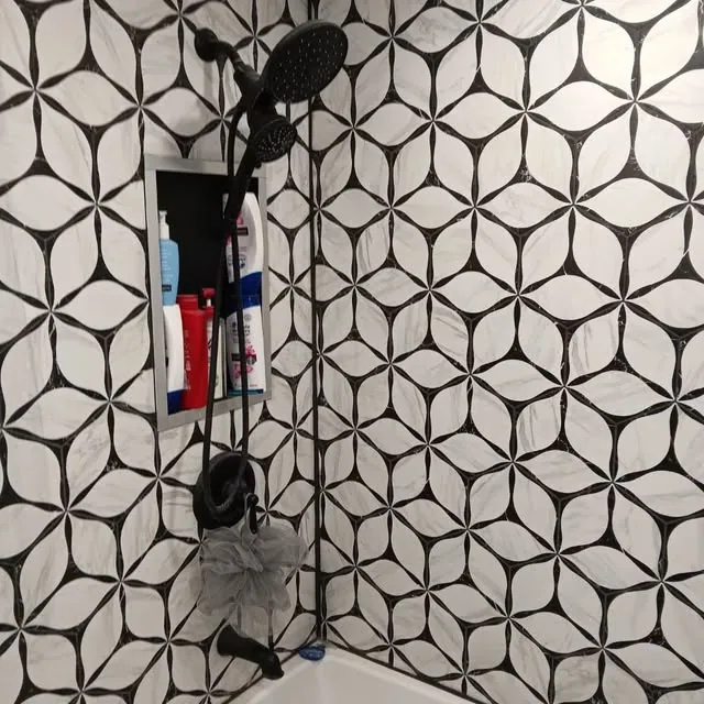 Black-and-white patterned shower tile with recessed niche and black fixtures