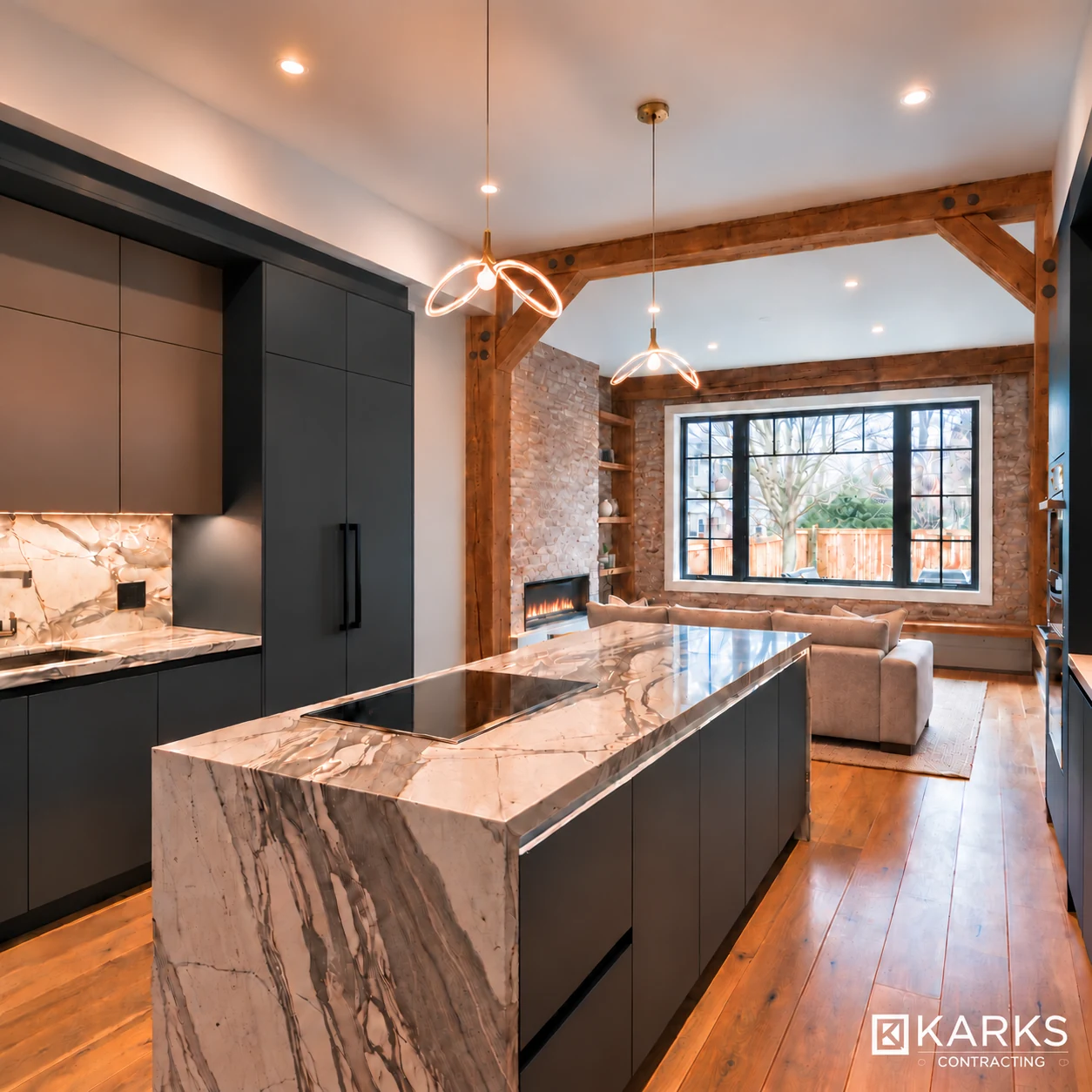 Completed kitchen renovation with dark cabinets, a stone island and an open view to the living room