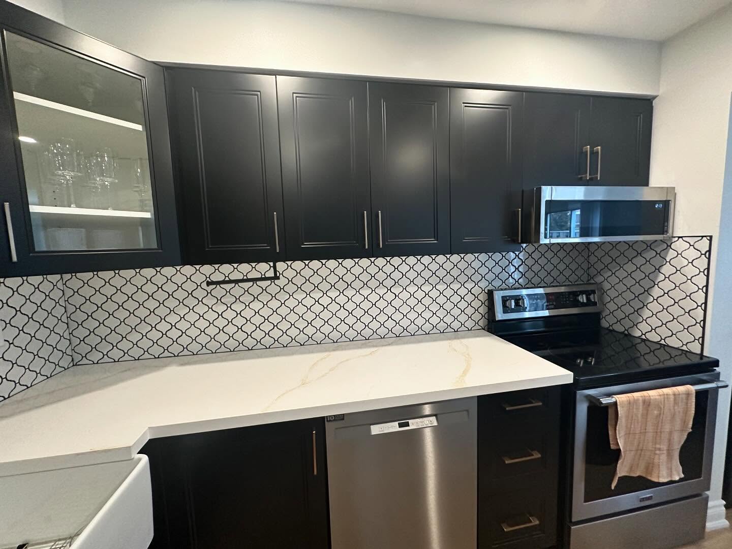 Dark kitchen cabinetry with a patterned backsplash and durable work surfaces